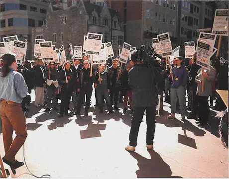 Picketers around a person with a microphone.